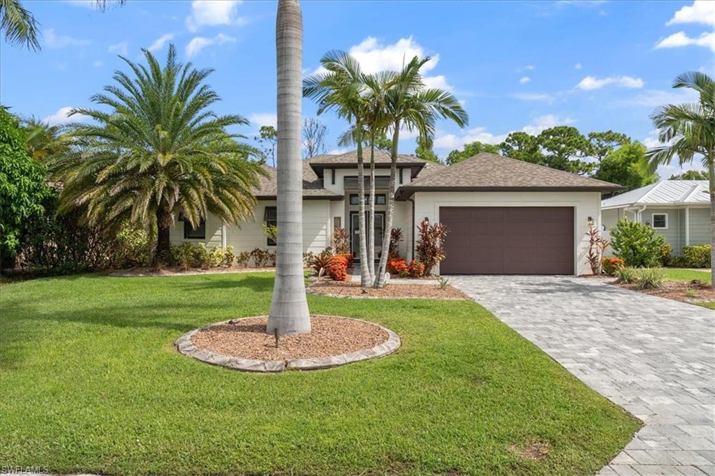 a front view of a house with a yard and palm trees
