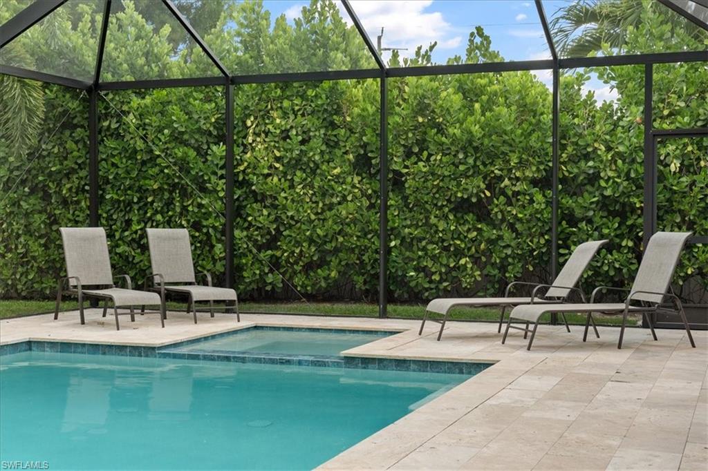 3554 McComb Lane Bonita Springs, FL 34134 - Photo 20 of 25 a view of a swimming pool with a bench and lawn chairs under an umbrella