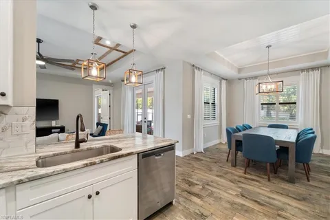 a dining hall with stainless steel appliances granite countertop a sink a dining table and chairs with wooden floor