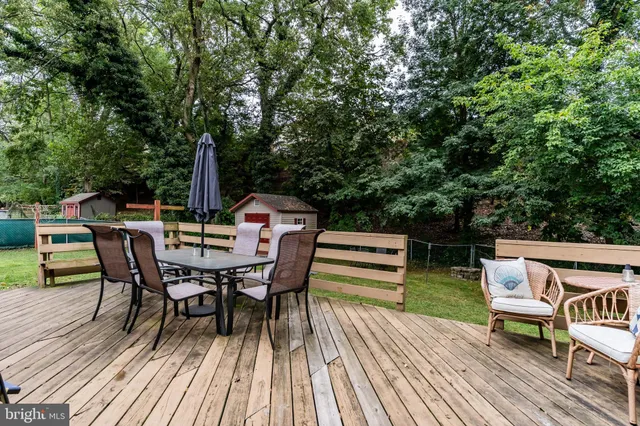 a view of a roof deck with table and chairs a barbeque with wooden floor and fence