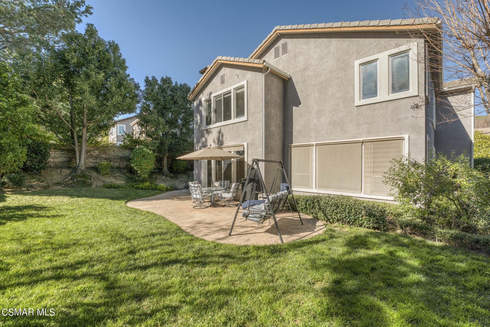 476 Woodland Road Simi Valley, CA 93065 - Photo 40 of 41 a white house with a yard and table and chairs under an umbrella