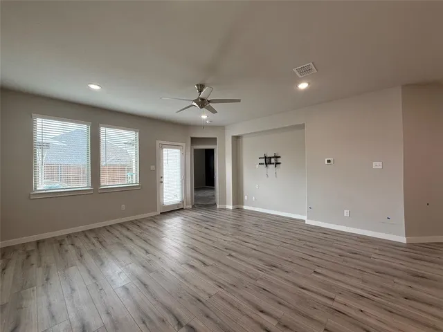 a view of an empty room with window and wooden floor