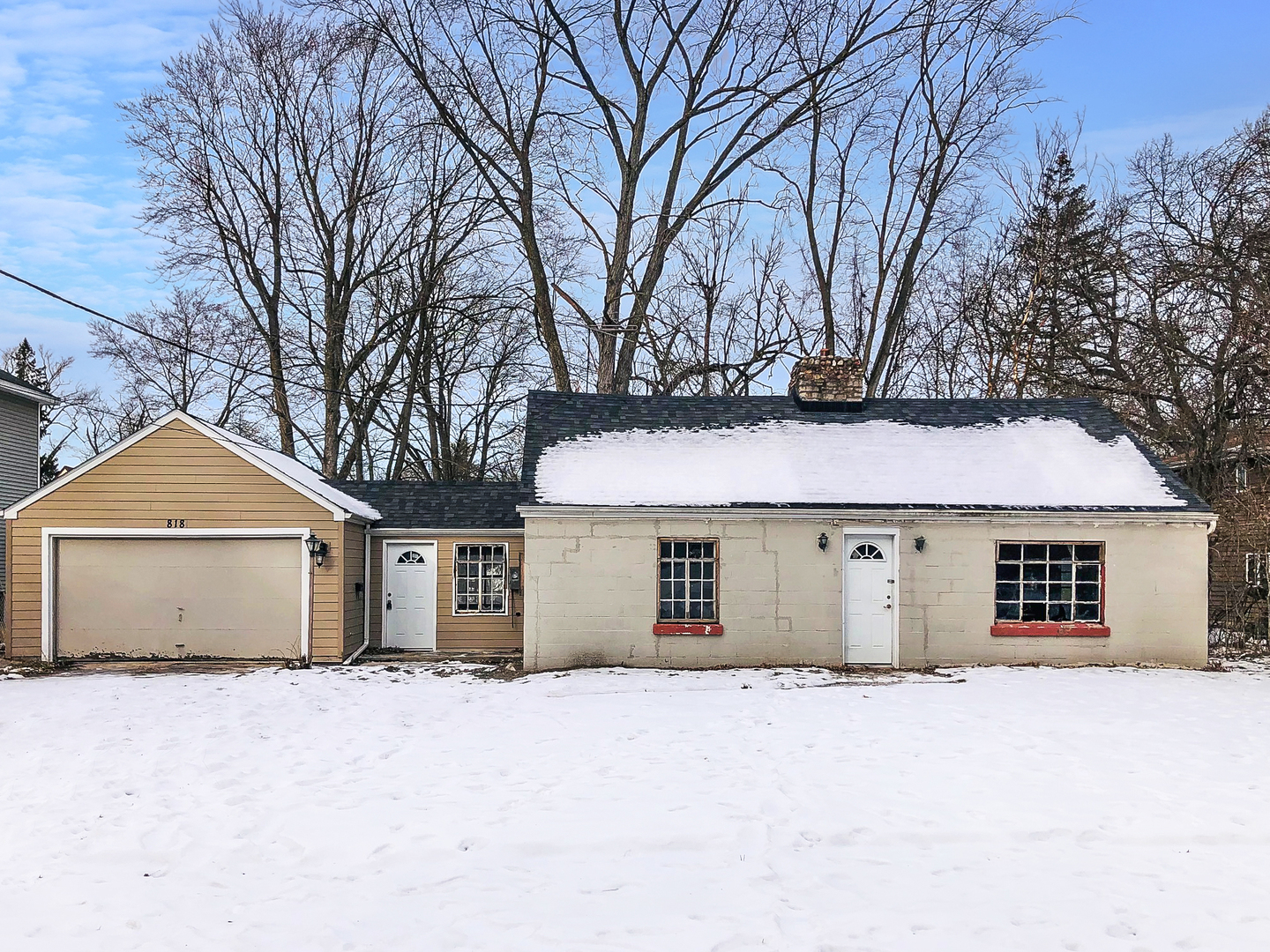 a front view of a house with a yard and covered with snow