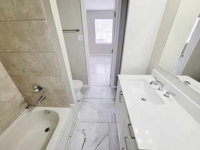 a bathroom with a tub sink and mirror