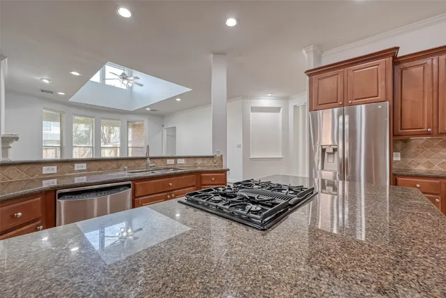 a kitchen with stainless steel appliances granite countertop a stove a sink dishwasher and a refrigerator
