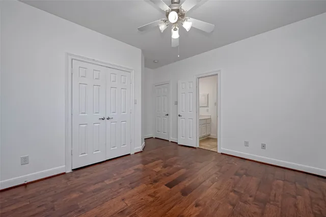 an empty room with wooden floor chandelier fan and windows