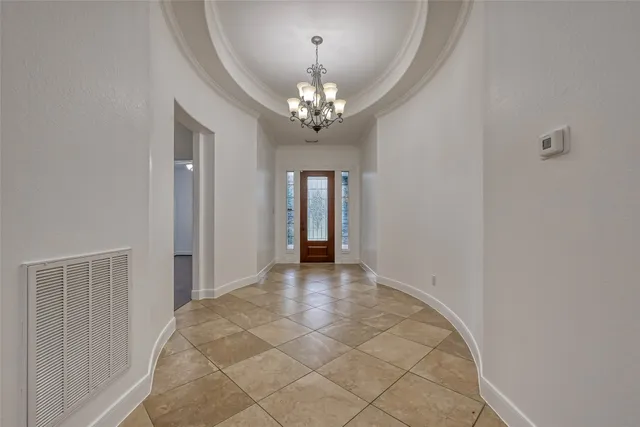 a view of an empty room with chandelier fan and fire place