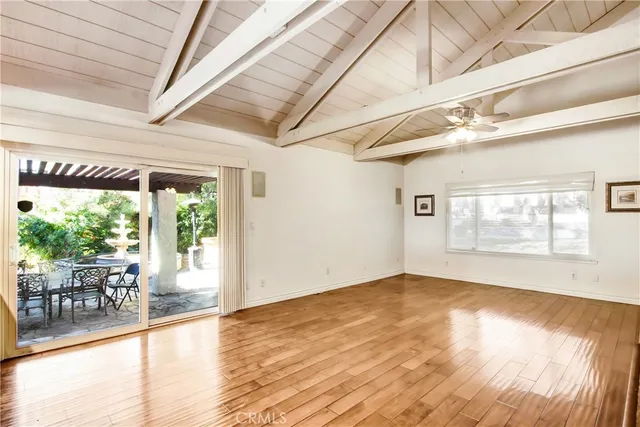 an empty room with wooden floor fireplace and windows