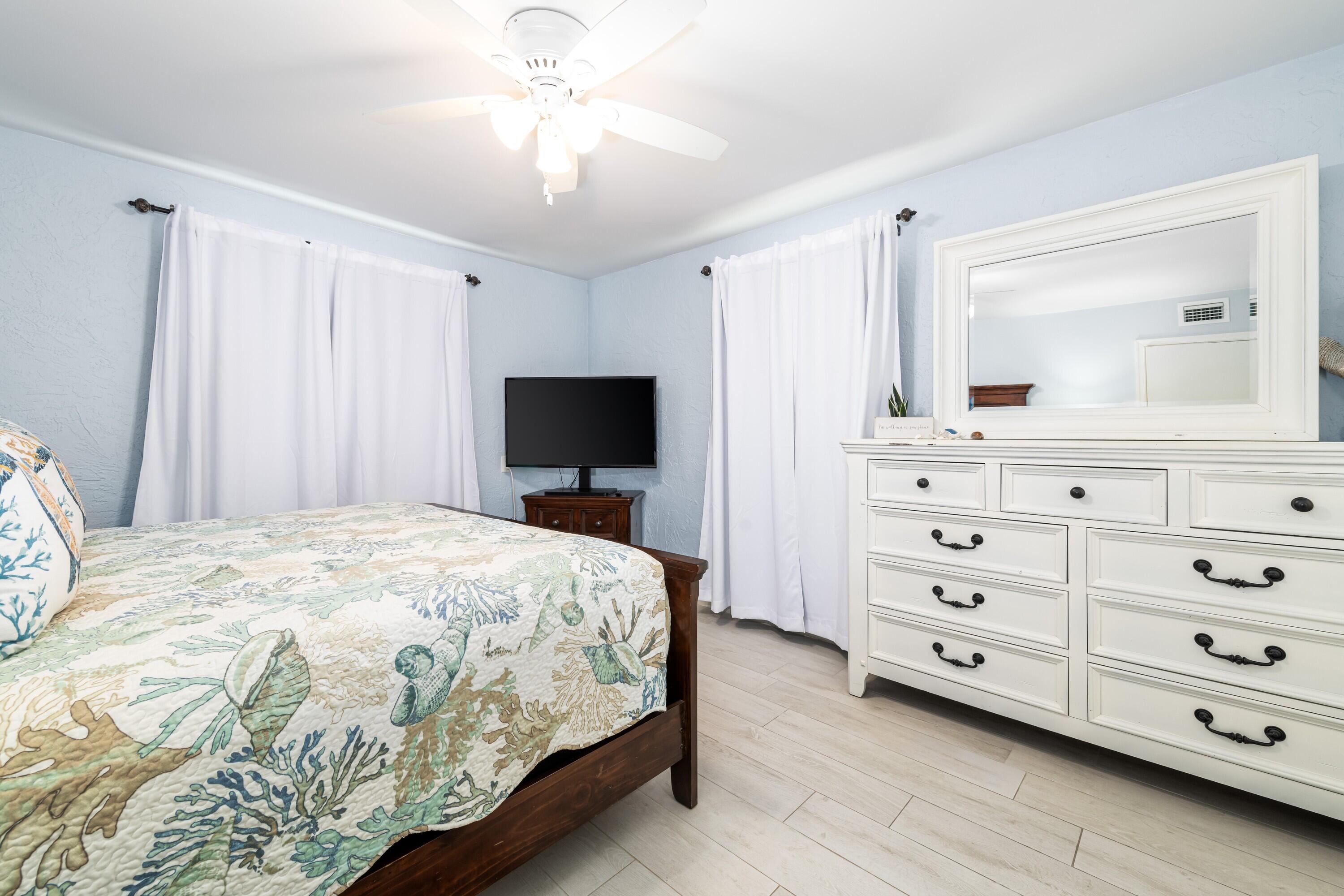 105 Ave D, Unit 101 Marathon, FL 33050 - Photo 19 of 32 a bedroom with a bed a chandelier and a television