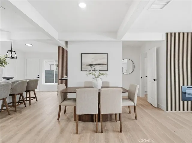 a kitchen with stainless steel appliances granite countertop a sink a stove a dining table and chairs with wooden floor