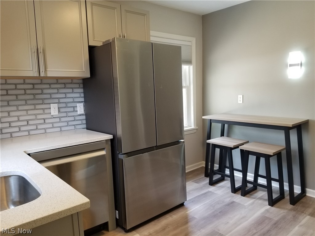 5671 Wellington Road Cleveland, OH 44124 - Photo 7 of 26 Kitchen with tasteful backsplash, stainless steel appliances, cream cabinetry, light wood-type flooring, and light stone counters