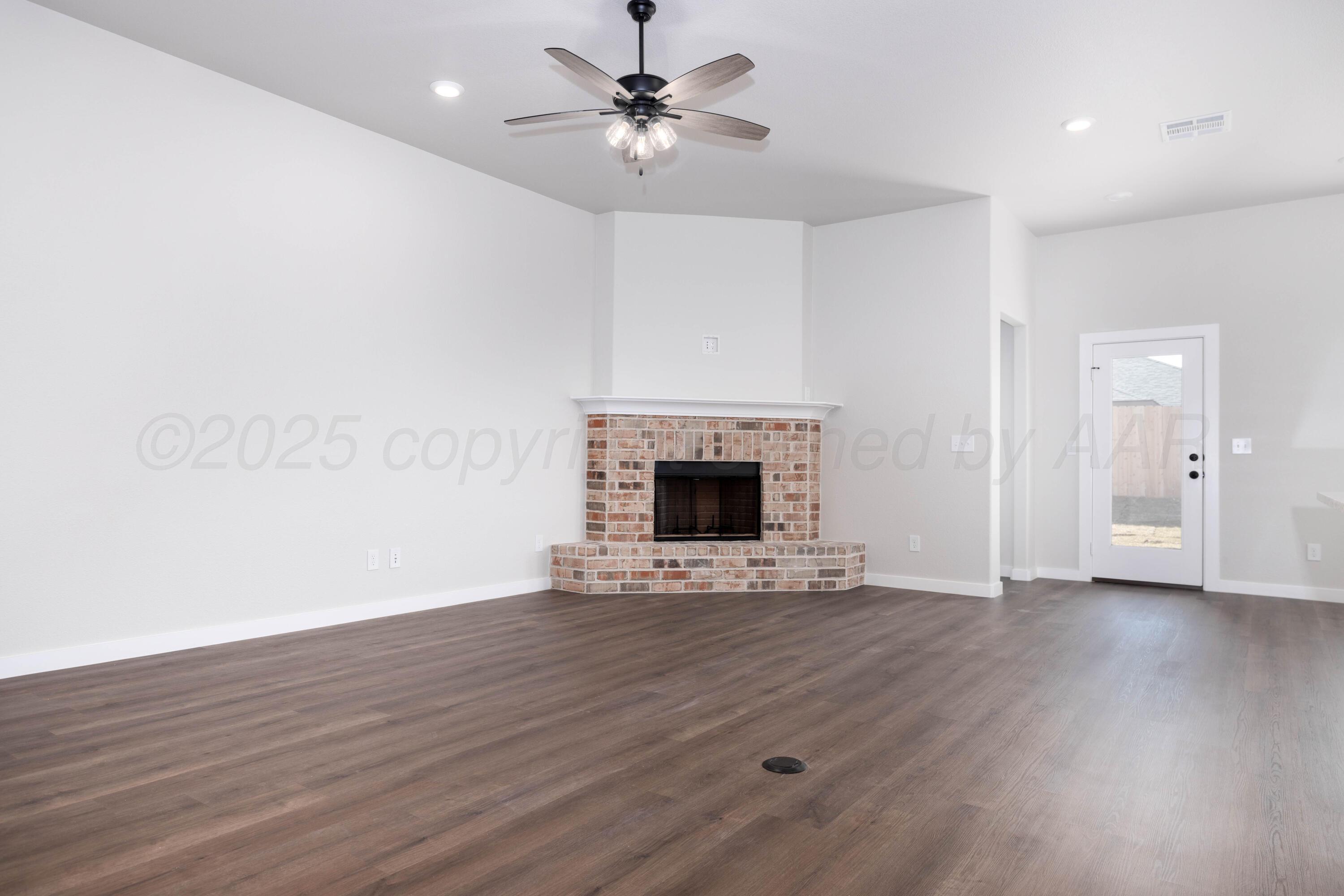 3012 Buckthorn Drive Amarillo, TX 79124 - Photo 9 of 9 an empty room with wooden floor a ceiling fan a fireplace and windows