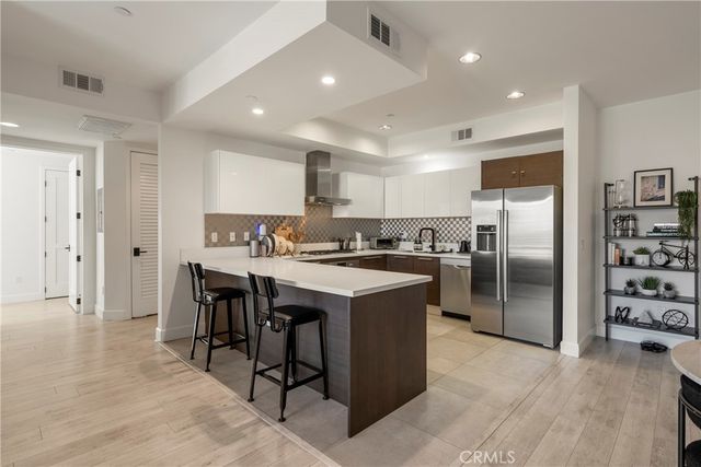 a kitchen with stainless steel appliances granite countertop a refrigerator a sink a stove a dining table and chairs