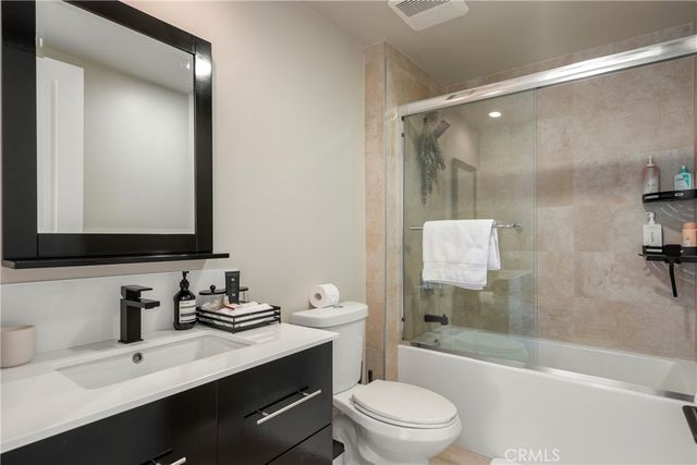 a bathroom with a bathtub shower sink vanity mirror and toilet