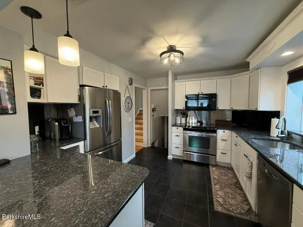 a kitchen with stainless steel appliances granite countertop a sink a stove and refrigerator