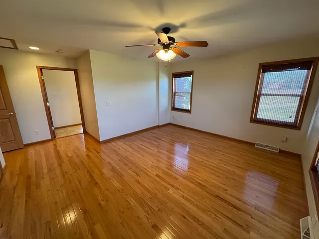 an empty room with a chandelier fan and a window
