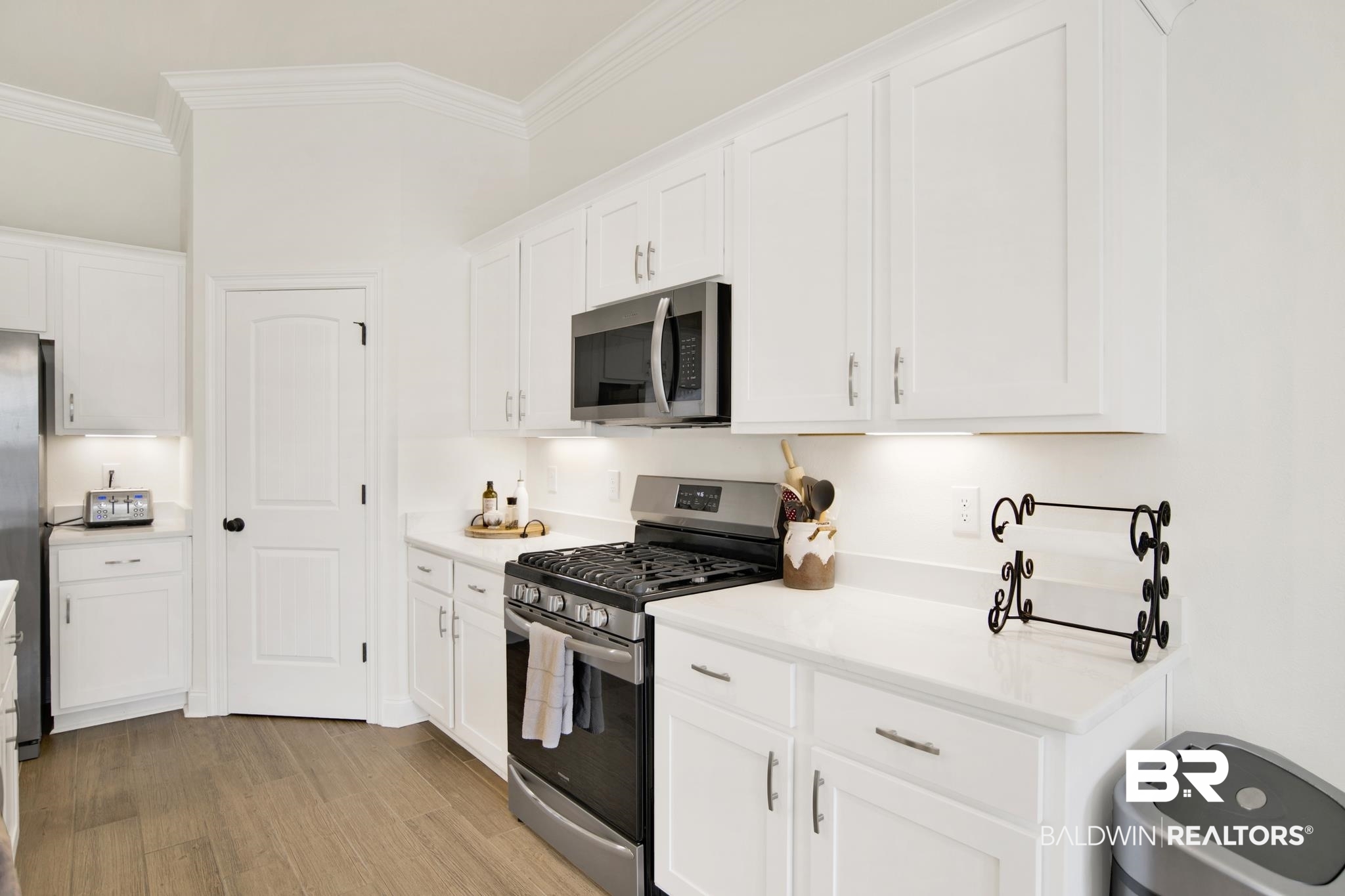 22258 Hibiscus Circle Foley, AL 36535 - Photo 8 of 26 Kitchen featuring light wood finished floors, ornamental molding, white cabinetry, stainless steel appliances, and light countertops
