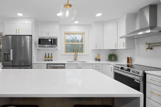 a kitchen with stainless steel appliances a sink a stove a refrigerator cabinets and a window