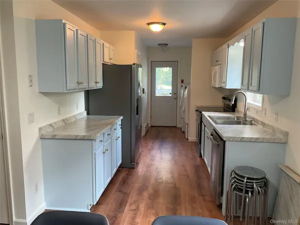 a kitchen with a sink a refrigerator and wooden floor