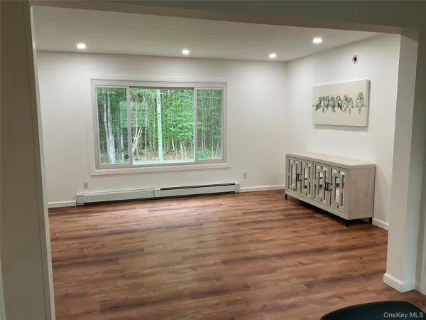 a view of an empty room with a window and wooden floor
