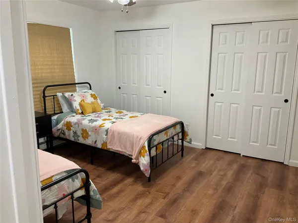 a bedroom with a bed a table and wooden floor