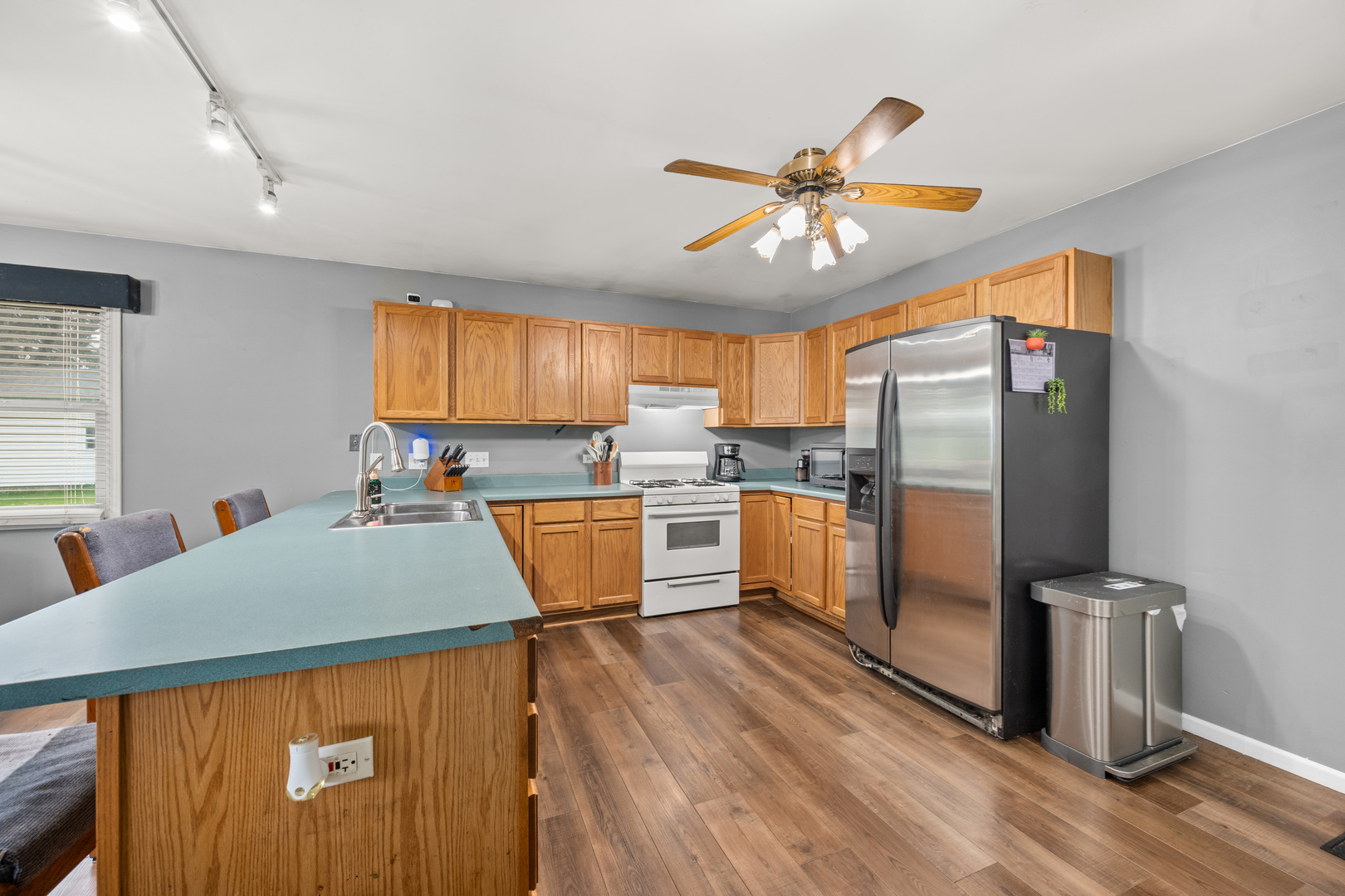 323 West Church Street Genoa, IL 60135 - Photo 7 of 28 a kitchen with stainless steel appliances a refrigerator a sink dishwasher a stove and white countertops with wooden floor