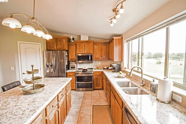a kitchen with kitchen island granite countertop a sink stove and refrigerator