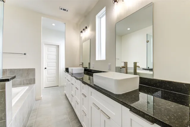 a spacious bathroom with a sink double vanity granite and a mirror