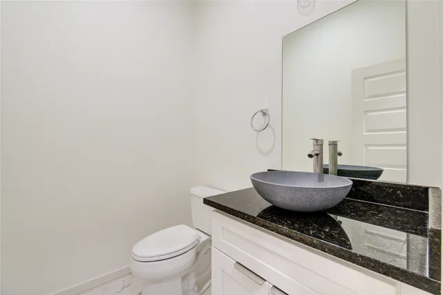 a bathroom with a granite countertop toilet and a sink