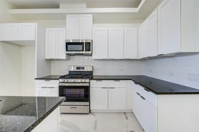 a kitchen with granite countertop white cabinets and stainless steel appliances