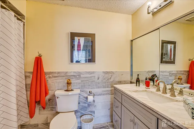 a bathroom with a granite countertop sink mirror vanity and toilet