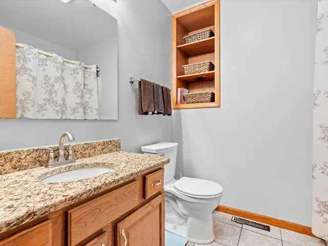 a bathroom with a granite countertop sink and a toilet