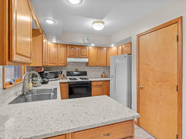 a kitchen with granite countertop a refrigerator stove top oven and sink