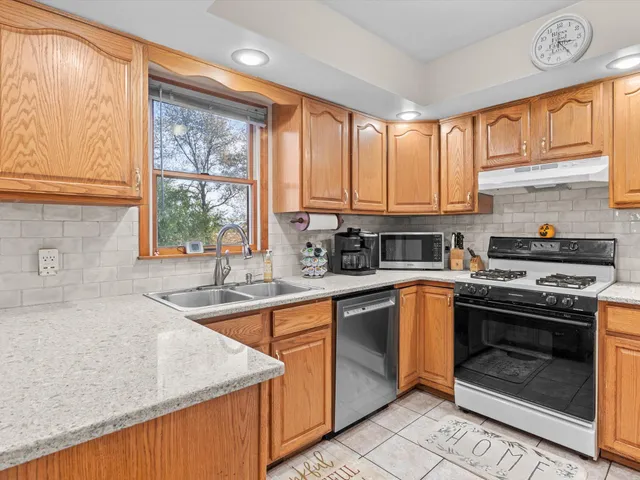 a kitchen with stainless steel appliances granite countertop a stove a sink and a microwave