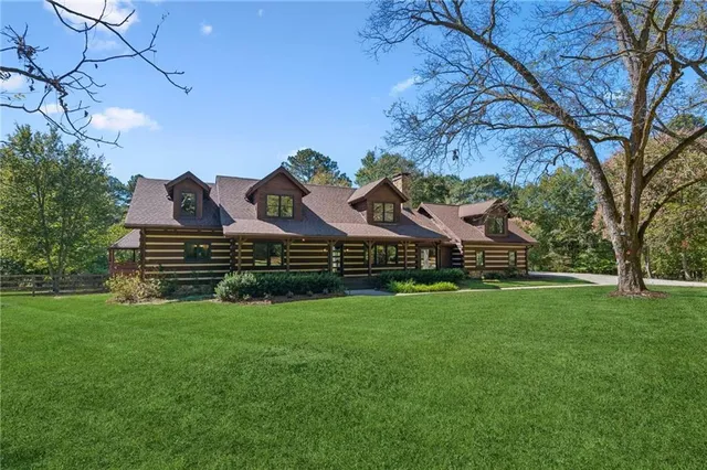 a view of a house with a big yard and large trees