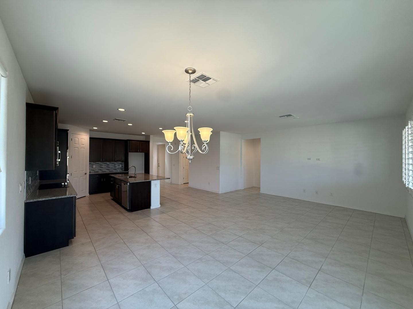 15744 West Jefferson Street Goodyear, AZ 85338 - Photo 14 of 26 an empty room with kitchen view and a chandelier