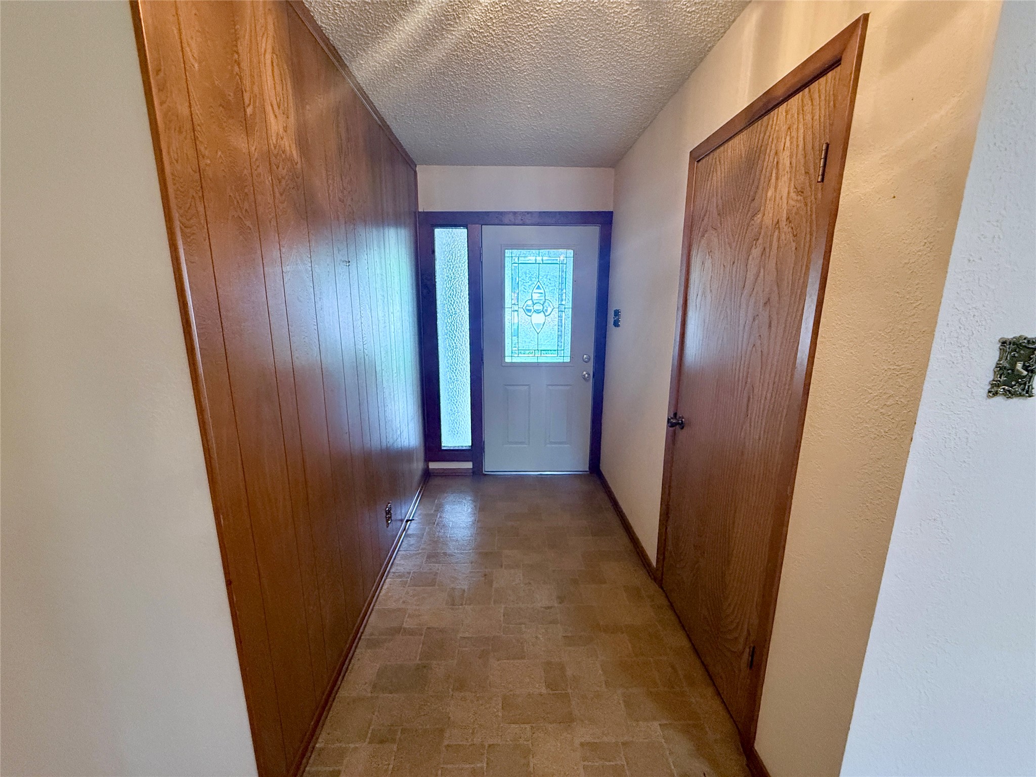 Front entry doorway to outside featuring wood walls