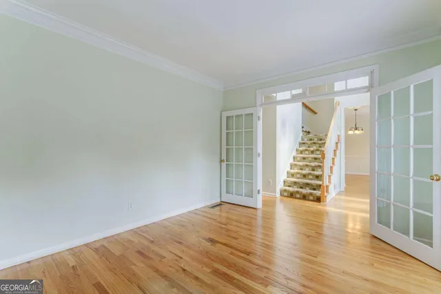 a view of empty room with wooden floor and fan