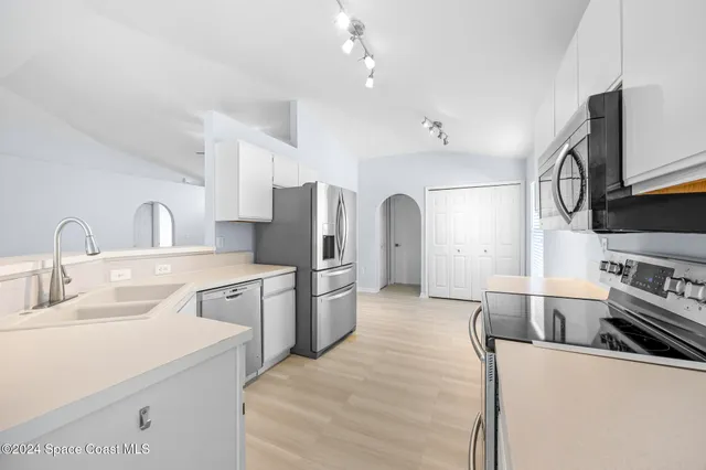 a large white kitchen with stainless steel appliances