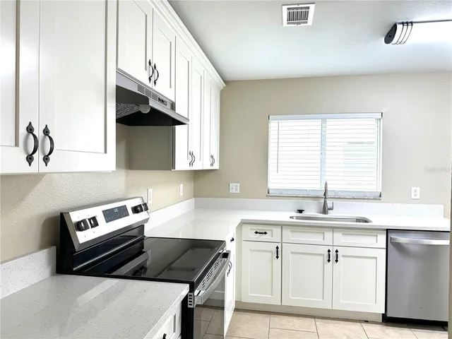 a kitchen with granite countertop a sink a stove and cabinets