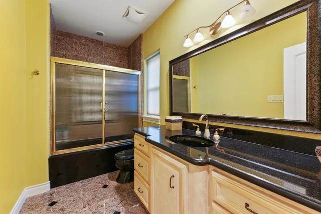 a bathroom with a granite countertop sink toilet a mirror and shower