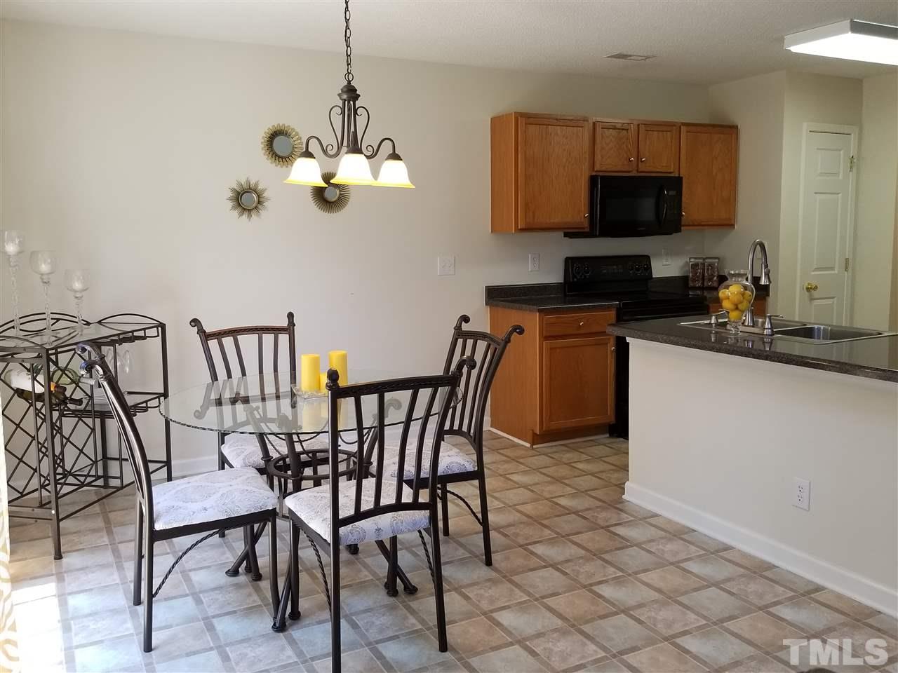 5832 Ricker Road Raleigh, NC 27610 - Photo 4 of 14 a kitchen with stainless steel appliances granite countertop a sink a stove a microwave with a dining table and chairs