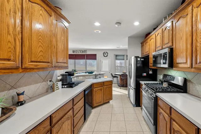 a kitchen with stainless steel appliances a sink dishwasher stove refrigerator and cabinets