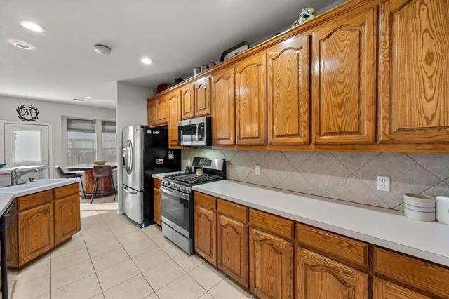 a kitchen with stainless steel appliances granite countertop a sink dishwasher stove and refrigerator with wooden cabinets