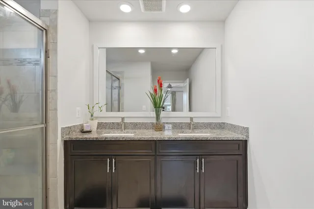 a bathroom with a granite countertop shower a mirror and a sink