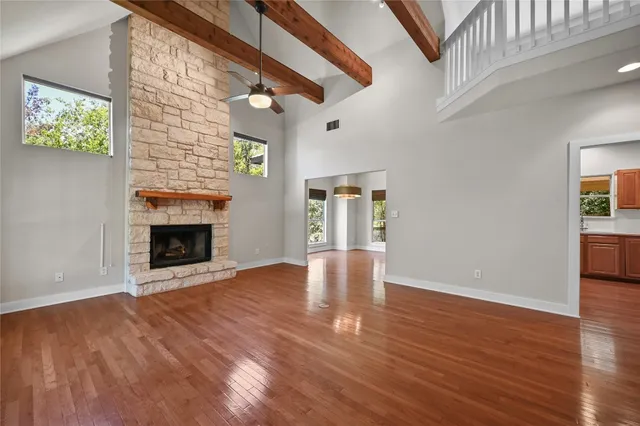 a view of an empty room with wooden floor fireplace and a window