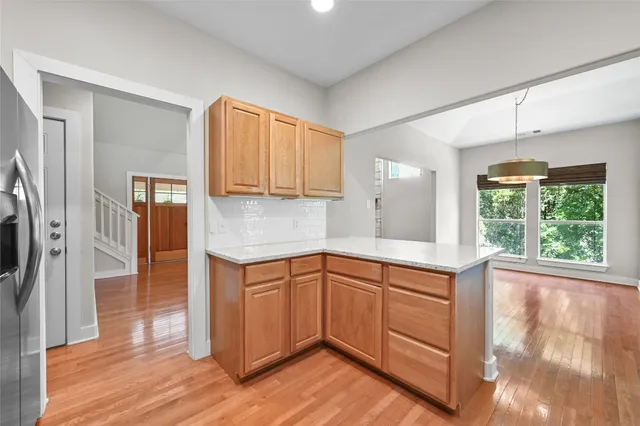 a kitchen with stainless steel appliances granite countertop a stove a sink and a refrigerator with wooden floors