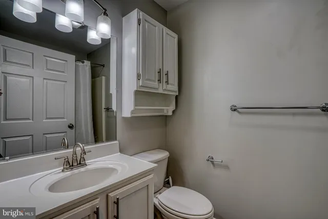 a bathroom with a sink vanity granite and toilet