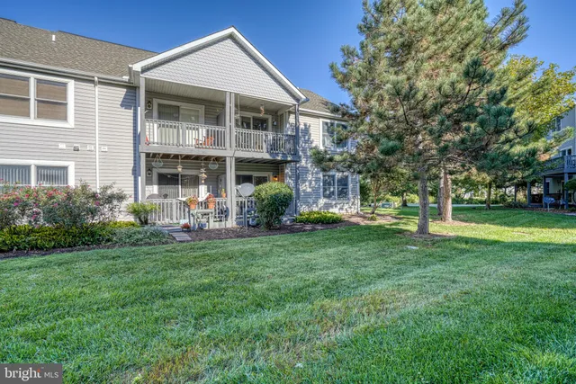 a front view of a house with a garden and trees