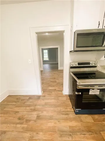 a view of kitchen and empty room with wooden floor